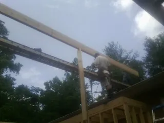Carpenter setting a ridge beam over a new addition frame — Ice Dam Removal by Roofing Brothers in Malvern
