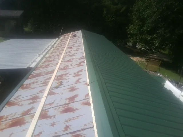 Old rusted panels beside newly installed green metal roofing — Wind Damage Roof Repair by Roofing Brothers in Malvern