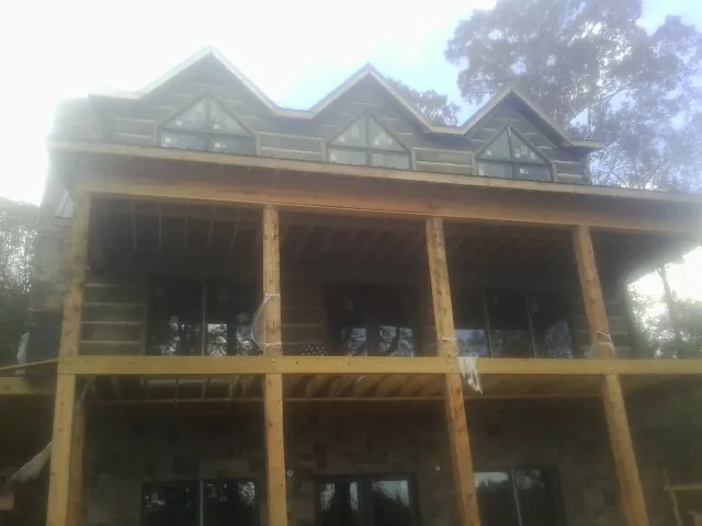 Dormers and porch framing on a large log home under construction — Roof Coating work by our crew in Malvern